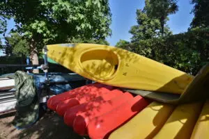 Cette image capture l'énergie vibrante des kayaks jaunes et rouges au soleil, sur une plage verdoyante, en pleine nature, idéale pour des aventures aquatiques estivales en Corse.
